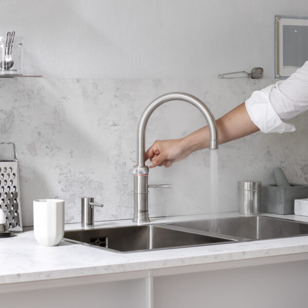 Quooker Fusion Square boiling water tap dispensing water into a glass in a modern kitchen