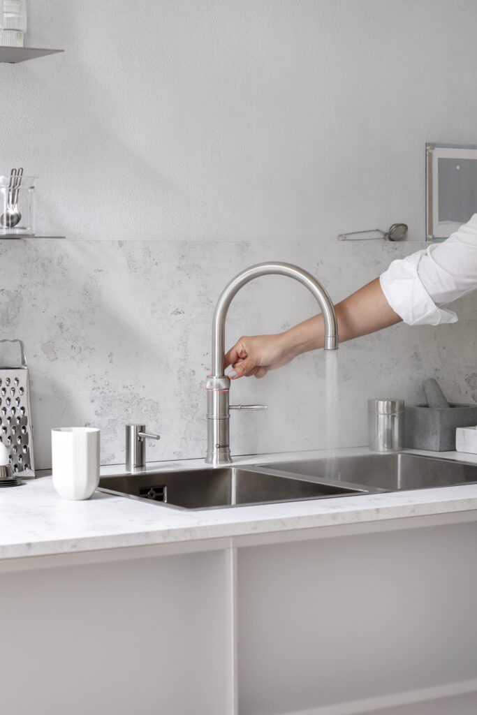 Quooker Fusion Square boiling water tap dispensing water into a glass in a modern kitchen